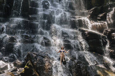 Junge Frau in der Nähe des Kanto Lampo Wasserfalls, Bali, Indonesien - KNTF03849