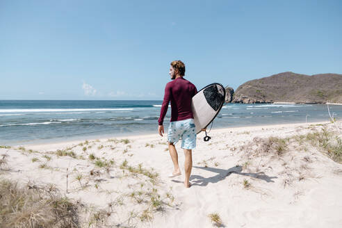 Mann mit Surfbrett am Strand, Insel Sumbawa, Indonesien - KNTF03851