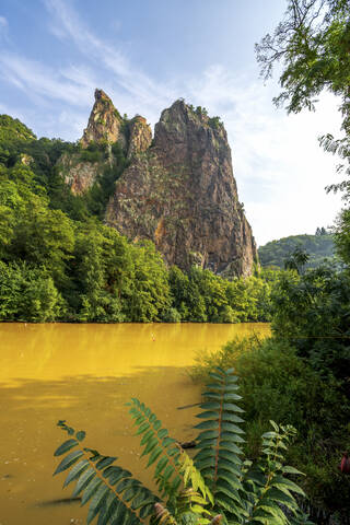 Germany, Rhineland-Palatinate, Bad Munster am Stein-Ebernburg, Yellow Nahe river with Rheingrafenstein rock formation in background stock photo