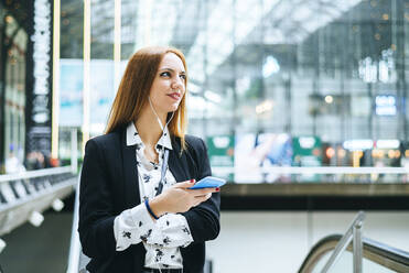 Young woman with earphones and cell phone at train station - KIJF02866