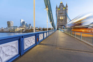 UK, England, London, Unscharfe Bewegung eines Doppeldeckerbusses, der in der Morgendämmerung über die Tower Bridge fährt - WPEF02417