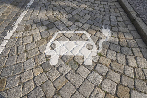 Germany, Saxony-Anhalt, Quedlinburg, Electric car charging station symbol on cobblestone - PVCF01323