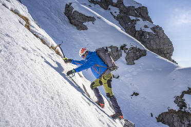 Alpinist beim Aufstieg auf einen verschneiten Berg, Orobie Alpen, Lecco, Italien - MCVF00148