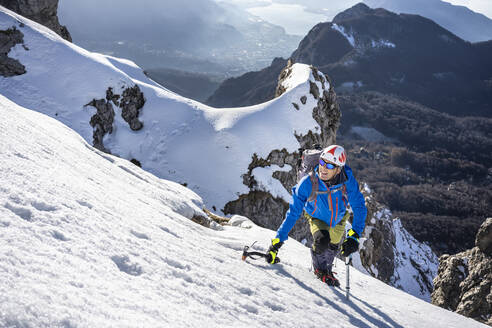 Alpinist beim Aufstieg auf einen verschneiten Berg, Orobie Alpen, Lecco, Italien - MCVF00151