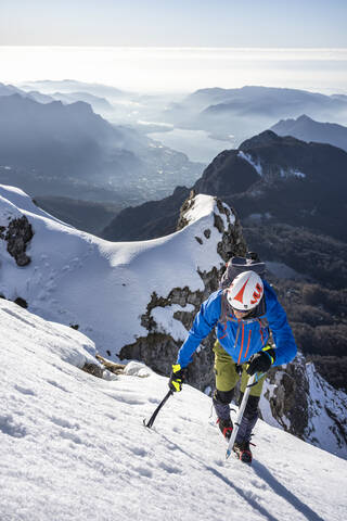 Alpinist beim Aufstieg auf einen verschneiten Berg, Orobie Alpen, Lecco, Italien, lizenzfreies Stockfoto