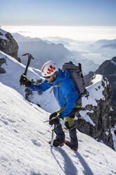 Alpinist beim Aufstieg auf einen verschneiten Berg, Orobie Alpen, Lecco, Italien - MCVF00154