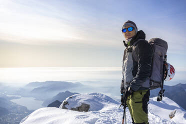 Portrait of an alpinist standing on snowy mountain peak, Orobie Alps, Lecco, Italy - MCVF00155