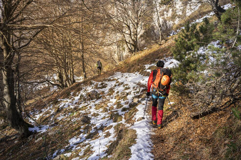 Zwei Wanderer, die durch einen verschneiten Wald wandern, Orobie Alpen, Lecco, Italien - MCVF00156