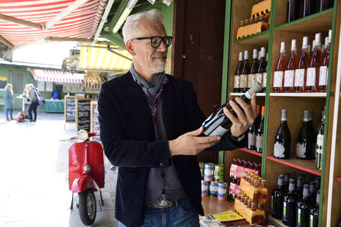 Reifer Mann wählt eine Flasche Wein in einer Weinhandlung aus - ECPF00831