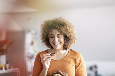 Lächelnde Frau im mittleren Erwachsenenalter, die einen Keks isst, lizenzfreies Stockfoto