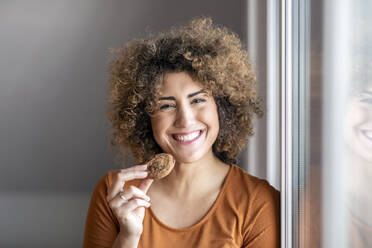 Smiling mid adult woman eating a cookie - FMKF06061