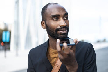 Porträt eines jungen Geschäftsmannes, der sein Handy im Freien benutzt - JSRF00698