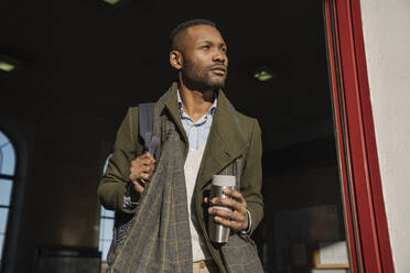 Stylish man with reusable cup getting out of the train station - AHSF01608