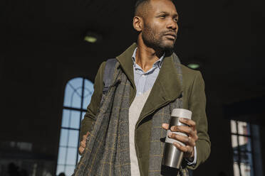 Stylish man with reusable cup getting out of the train station - AHSF01610