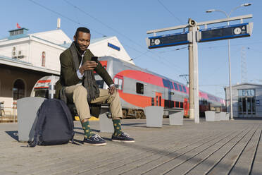 Stilvoller Mann mit Smartphone beim Warten auf den Zug - AHSF01620