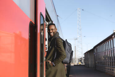 Porträt eines glücklichen Mannes, der in einen Zug einsteigt - AHSF01631