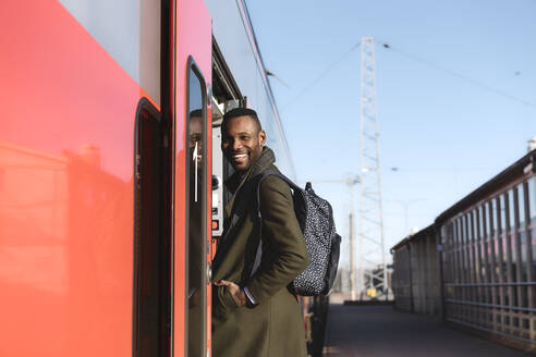 Portrait of happy man entering a train - AHSF01631