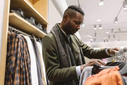 Stylish man shopping in a clothes store - AHSF01641