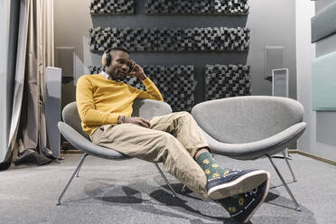 Man with headphones sitting in armchair - AHSF01648