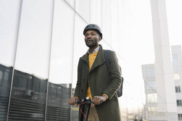 Portrait of stylish man with helmet and scooter in the city - AHSF01658