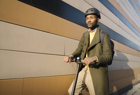 Stylish man with helmet and scooter at a building - AHSF01661