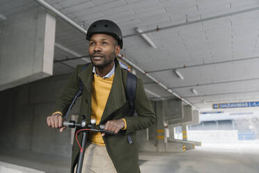 Porträt eines stilvollen Mannes mit Helm und Motorroller in der Stadt - AHSF01662