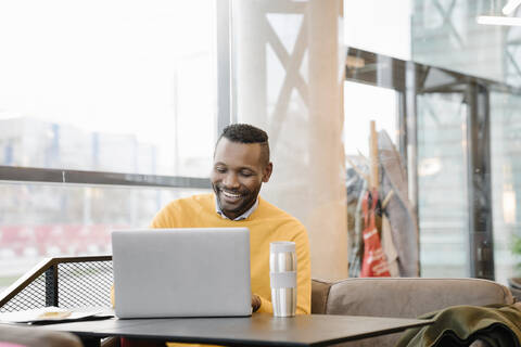 Glücklicher Mann mit Laptop in einem Café, lizenzfreies Stockfoto