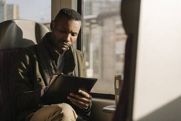 Stylish businessman taking notes while traveling by train - AHSF01687