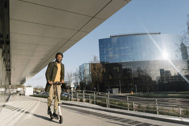 Stilvoller Mann mit Helm auf einem Motorroller in der Stadt - AHSF01690