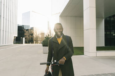 Portrait of happy man with scooter in the city - AHSF01691