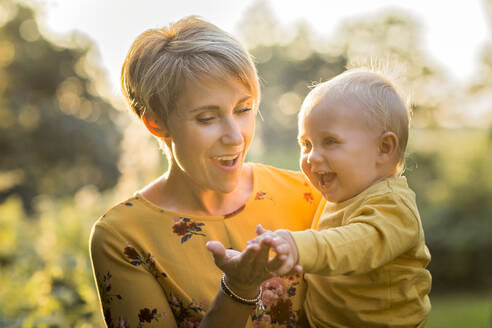 Porträt einer glücklichen Mutter mit ihrem kleinen Sohn im Gegenlicht - NMSF00385