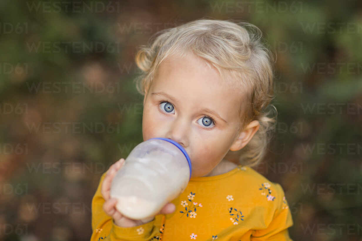 Toddler girl drinking water from the baby bottle Stock Photo