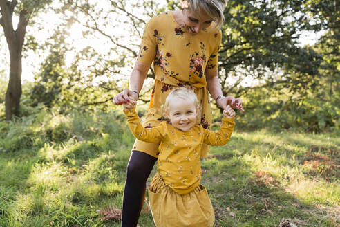 Portrait of little blond girl hand in hand with her mother on a meadow - NMSF00401