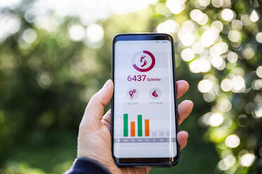 Frau hält Smartphone und nutzt Fitness-App - MAMF00991