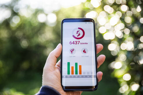 Frau hält Smartphone und nutzt Fitness-App - MAMF00991