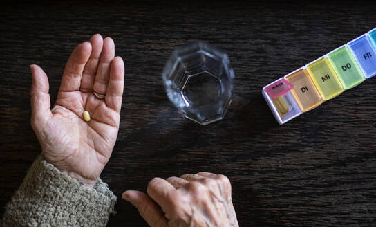 Ältere Frau bei der Einnahme von Medikamenten, Wasserglas und Pillenorganisator - MAMF00995