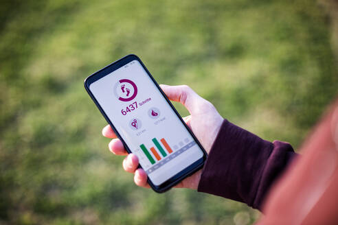 Mann hält Smartphone und nutzt Fitness-App - MAMF00997