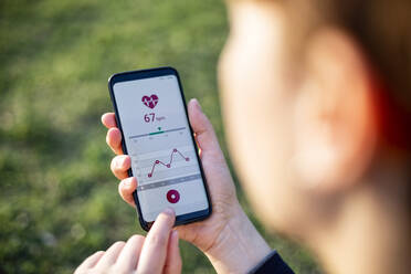 Frau hält Smartphone und nutzt Fitness-App - MAMF00998