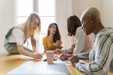 Businesswomen having a meeting and taking notes in office - AFVF04718