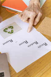 Geschäftsfrau, die auf Papier mit Recycling-Symbol im Büro zeigt - AFVF04741