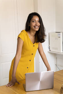 Porträt einer lächelnden Geschäftsfrau mit Laptop im Büro - AFVF04753