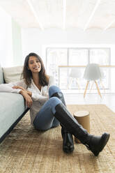 Portrait of self-confident young woman sitting on the floor of a studio - AFVF04765