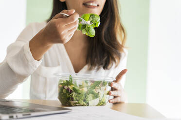 Crop-Ansicht eines jungen Architekten, der am Schreibtisch einen gemischten Salat isst - AFVF04771