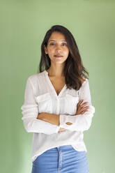 Porträt einer jungen Geschäftsfrau vor einer grünen Wand - AFVF04780