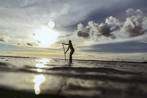 Female SUP surfer at sunset, Bali, Indonesia - KNTF03896