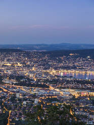 Switzerland, Canton of Zurich, Zurich, City surrounding edge of Lake Zurich seen from Uetliberg at dusk - WDF05646