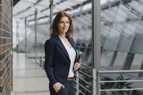 Selbstbewusste Geschäftsfrau mit einem Tablet in einem modernen Bürogebäude, lizenzfreies Stockfoto