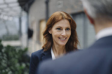Porträt einer lächelnden Geschäftsfrau im Gespräch mit einem Geschäftsmann im Büro - JOSF04160
