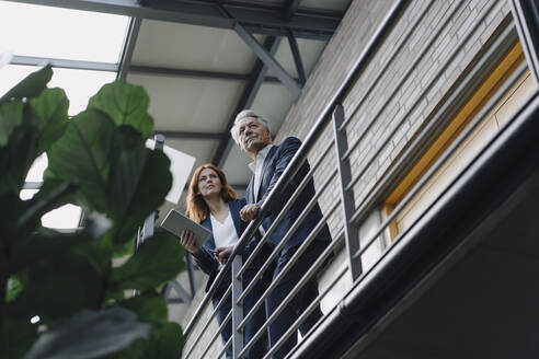 Geschäftsmann und Geschäftsfrau mit Tablet in einem modernen Bürogebäude stehend - JOSF04173