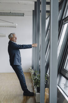 Senior businessman holding girder in office - JOSF04195